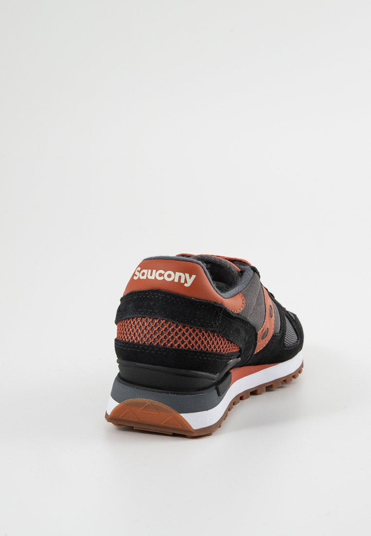 Sneaker nera con accenti arancioni, materiali in suede e mesh, colletto imbottito e una suola intermedia bianca con suola in gomma testurizzata.