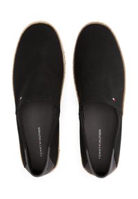 Zapatos negros sin cordones con parte superior de lona texturizada, puntera redonda y suela de yute estilo espadrille. Presenta el logo en la plantilla y un pequeño emblema en el lado.