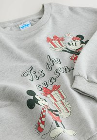 Maglione grigio con scollo rotondo, caratterizzato da una stampa di Topolino e Minnie Mouse che reggono dei regali, accompagnata dal testo "È tempo di festa".