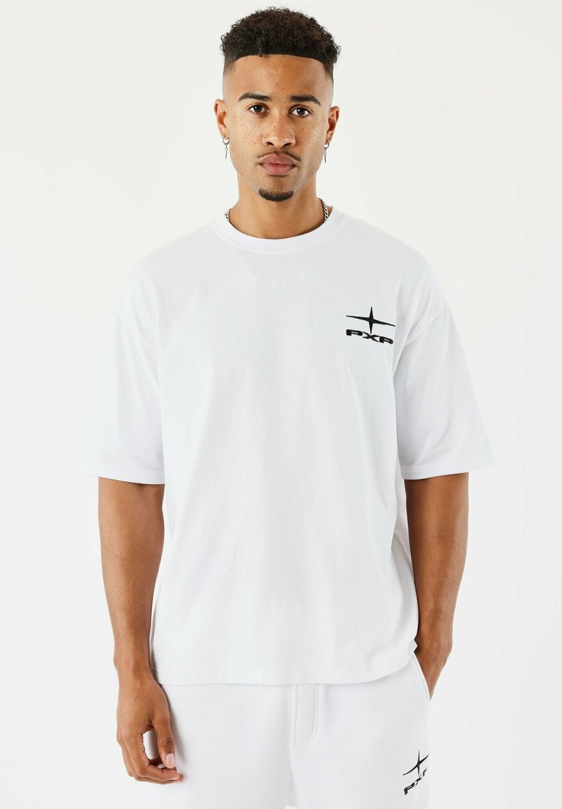 T-shirt bianco in cotone con maniche corte, caratterizzata da un logo stampato in nero nella zona sinistra del petto. Vestibilità ampia e texture morbida.