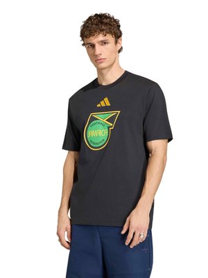 Giovane uomo con capelli ricci che indossa una maglietta nera della Federazione di Calcio della Giamaica e pantaloncini blu, in piedi davanti a uno sfondo bianco.