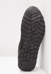 Semelle de botte noire avec des motifs de semelle en zigzag profond et chevrons, affichant le nom de la marque "Anna Field" au centre.