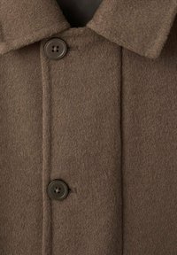 Cappotto di lana marrone con collo, due bottoni scuri e una texture morbida. Cuciture visibili lungo il frontale.