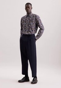 Camicia con bottoni a fantasia floreale in blu scuro, abbinata a pantaloni navy a vita alta e gamba larga e scarpe nere in pelle.