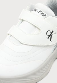 Λευκό sneaker Calvin Klein με δύο λουράκια με βέλκρο, επάνω μέρος από ύφασμα και δέρμα και παχύ, υφή πέλμα.
