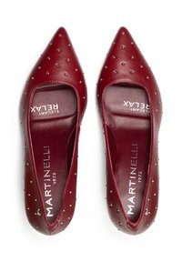 Bailarinas rojas de cuero con punta afilada, que presentan un diseño recortado y tachuelas plateadas en toda su superficie. En el interior incluye detalles de marca.
