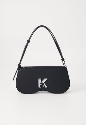 Sac à main noir avec une forme courbée, un matériau texturé, un logo argenté et une fine bandoulière. Fermeture zippée sur le dessus et caractéristiques de design minimalistes.