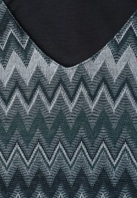 Motif tricot Chevron dans des tons de vert foncé, gris et noir avec un col arrondi sur un tissu textile.