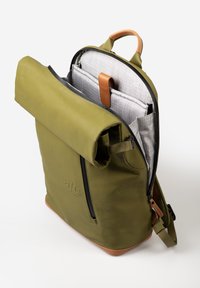 Zaino roll-top verde oliva con zip nera, dettagli in pelle marrone e interno a quadretti grigi. Presenta molteplici scomparti interni.