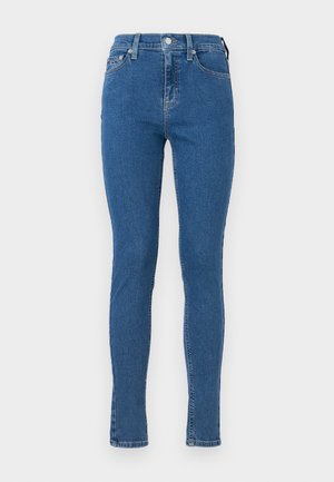 Kõrge vöökohaga sinised denimist teksad, slim fit lõikega, ees nupuga kinnitamine ja viis taskut, sile tekstuur ja minimaalne kulumine.