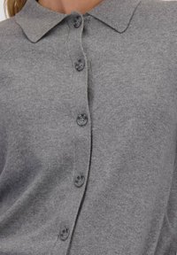 Grijze gebreide cardigan met een kraaglijn, voorzien van zes knoopsluitingen en een zachte, gestructureerde stof.