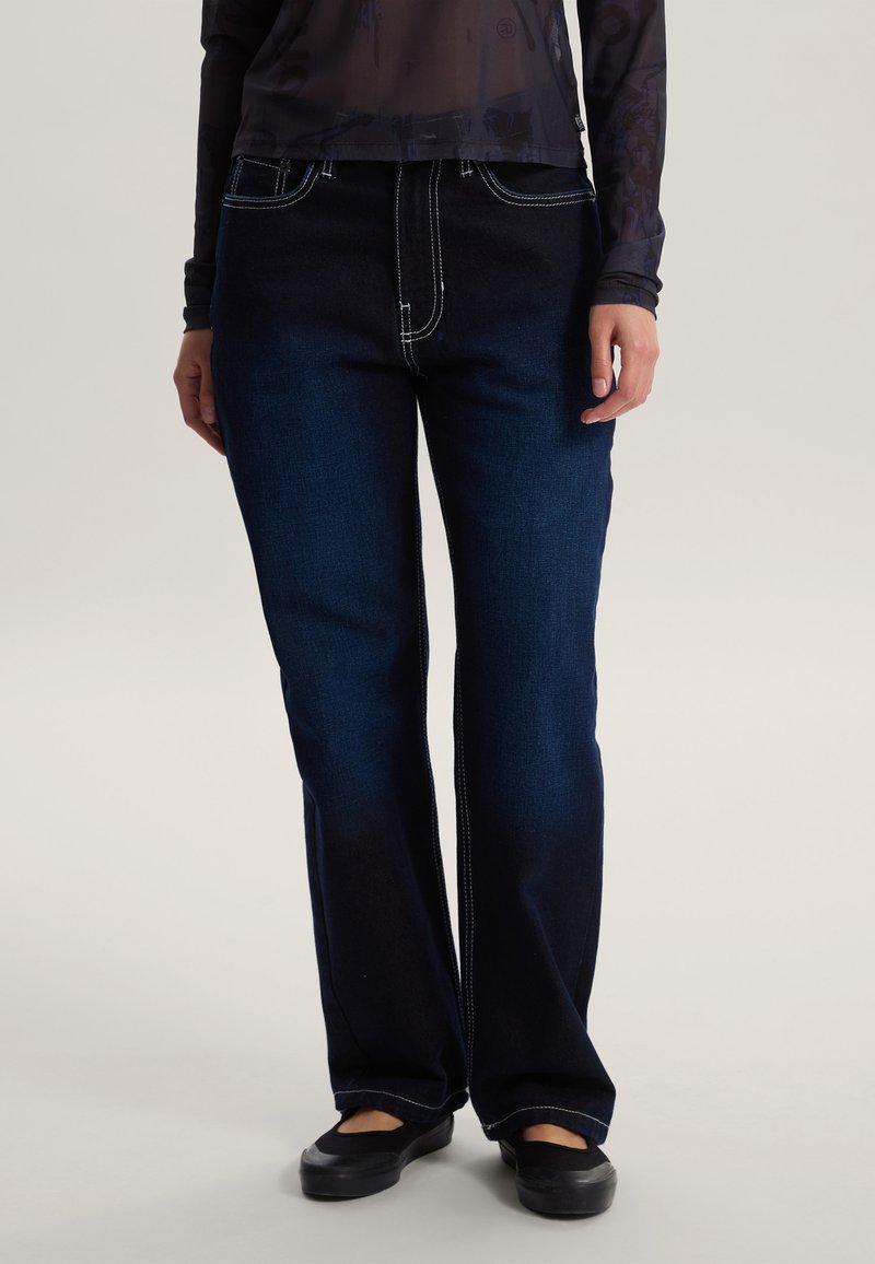 Jeans in denim blu scuro con cuciture a contrasto, design a gamba dritta, stile cinque tasche e leggero scolorimento sulle gambe.