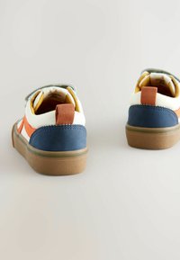 Multikleurige sneaker met een gestructureerde rubberen zool, blauwe en oranje accenten, een stoffen bovenwerk en een lusvormige trekband bij de hak.