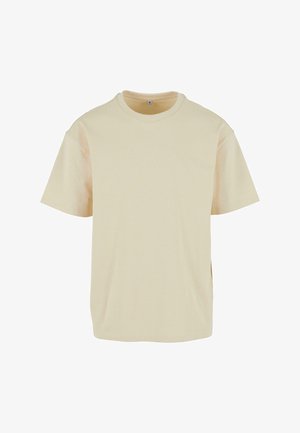 Beige bomull T-skjorte med korte ermer, rund hals og sidesplitter; glatt tekstur og avslappet passform.