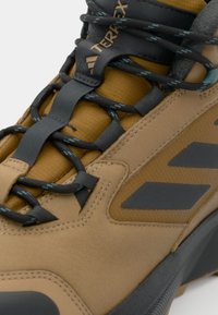 Nahaufnahme des braunen und schwarzen Adidas Terrex Wanderschuhs mit detaillierter Schnürung und strukturiertem Gewebe-Obermaterial.