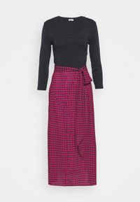 Mörkblus med långa ärmar som är parat med en rosa houndstooth inslagskjol med knytdetalj i midjan. Kjolen är knädlång och har en mjuk textur.