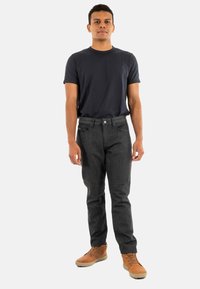 Jeans de un gris oscuro con un corte recto, cinco bolsillos y cierre de botón. Combinados con una camiseta de cuello redondo de color azul marino y zapatos beige.