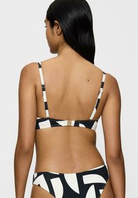 Bikini set in black and white, featuring geometric patterns. Thin adjustable straps and a clasp closure at the back for secure fit.