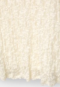 Tissu blanc texturé avec un design froncé et superposé, présentant des motifs complexes et des accents moelleux, idéal pour des vêtements ou des usages décoratifs.