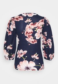 Floral blouse featuring a navy background, large pink flowers, and puff sleeves. Material has a smooth texture with a fitted waist.