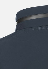 Colletto di camicia blu navy con una texture liscia, caratterizzato da una banda nera a contrasto e dettagli perforati sottili vicino alla cucitura della spalla.