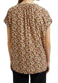 Blusa a fantasia floreale con un motivo di fiori crema e gialli su uno sfondo bordeaux, con scollatura a gathered e maniche corte.