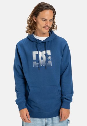 Marineblauwe hoodie van zachte stof met een voorkrui pocket, een capuchon met trekkoord en een groot wit logo met een ster. Ribbelboorden en -zoom.