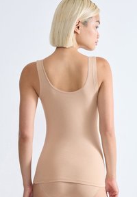 Canotta basic color beige chiaro, realizzata in morbido cotone, con scollatura a barca e spalline sottili, caratterizzata da un design liscio e aderente.