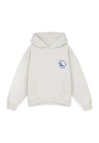 Sudadera con capucha de color crema hecha de tela suave. Presenta un bolsillo frontal y un gráfico de luna creciente azul con el texto "NO MOLESTAR".