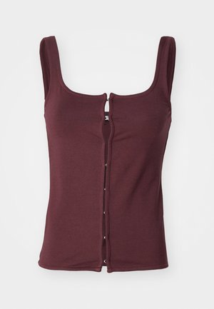 Bordeaux mouwloze top van zachte stof, met een ronde hals en een voorkantsluiting met zilverkleurige hardware en contrasterende stiksels.