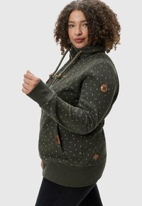 Sudadera verde oscura con un acabado texturizado, que presenta un patrón de pequeñas formas blancas y azules, un cuello alto y detalles de toggles de madera.