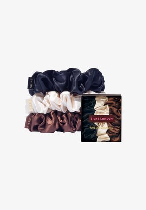 Ensemble de trois chouchous en soie de couleur bleu foncé, crème et marron chocolat. Livré dans une boîte noire avec du texte doré. Texture satinée douce.