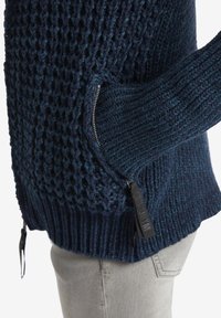 Námořnický pletený svetr s texturovaným vzorem a žebrovanými manžetami. Má boční kapsu na zip s kontrastním jezdcem. Měkká, silná pletenina.
