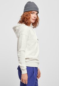 Hoodie kermanin ja mudatis, iin ribbed cuffs, valkoiset narut ja etutasku. Yhdistetty sinisiin narullisiin housuihin.