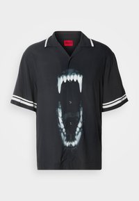 Chemise noire à manches courtes avec des rayures blanches sur les manches et un grand graphisme d'une bouche ouverte aux dents apparentes à l'avant.