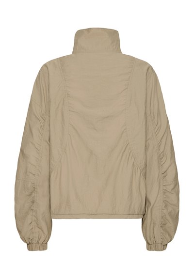 Veste légère beige avec un col montant, des manches froncées et un ourlet légèrement raccourci. Tissu lisse et texturé.