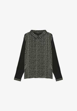 Camisa de manga larga en blanco y negro con un frente texturizado y con patrón y mangas negras lisas. Presenta un cuello y mangas con puños.