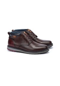 Brown leather boots with rounded toe, contrasting dark sole, and maroon accents. Features five-eyelet lacing and a textured finish.