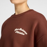 Sweatshirt castanho com gola redonda, punhos canelados e um logótipo bordado "New Balance Athletics" em creme. Textura suave.