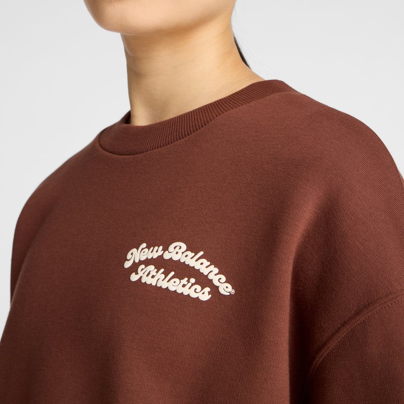 Brauner Sweatshirt mit Rundhals, gerippten Bündchen und einem eingewebten „New Balance Athletics“-Logo in Creme. Glatte Textur.