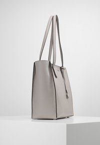 Borsa tote in pelle grigia con texture, doppi manici, design verticale, chiusura frontale con zip e dettagli in metallo discreti.