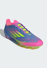 Blue and pink soccer cleat with a textured upper, yellow accents, and black stripes. Features a sleek design and translucent sole.