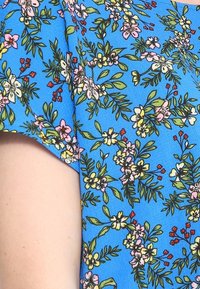 Modrá květinová blůza s různými malými květy a listy v růžové, bílé a zelené barvě na texturované látce. Krátké rukávy.