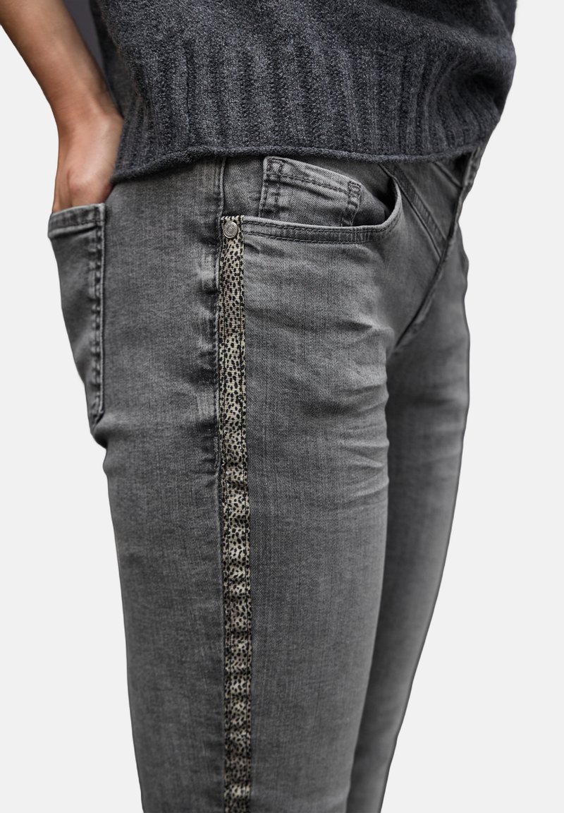 Vaqueros de mezclilla gris de corte slim, con un acento texturizado de estampado de leopardo a lo largo de la costura lateral y bolsillos tradicionales.