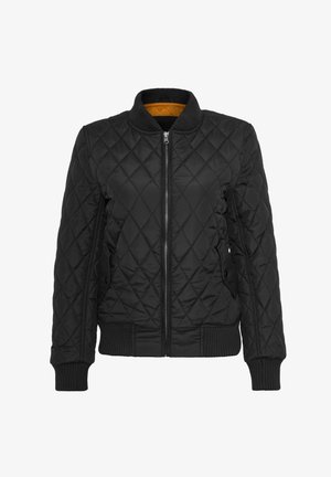 Czarna pikowana kurtka z zamkiem z przodu, ściągaczami na mankietach i kołnierzu. Posiada kontrastową, żółtą podszewkę. Gładka tekstura, diamentowy wzór.