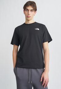 Μαύρο βαμβακερό T-shirt με κοντά μανίκια, που διαθέτει μικρό λευκό λογότυπο στο αριστερό στήθος. Το ύφασμα έχει ομαλή υφή και άνετη εφαρμογή.