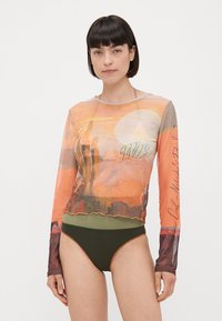 Top de manga larga y transparente con un gráfico de atardecer en tonos naranjas; combinado con braguitas de bikini de tiro alto en color verde oliva. Cuello circular y tejido texturizado.