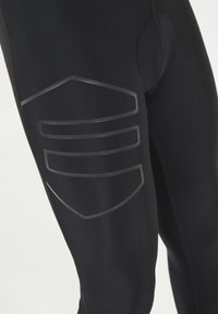 Svarta idrottsleggings gjorda av ett slätt tyg, med ett texturerat grått mönster på lårområdet och en snug passform runt midjan.