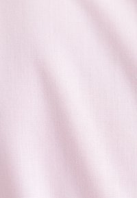 Weicher rosa Stoff mit feiner, dichter Strickstruktur und sanften Falten, die subtile Schatten und Lichtreflexe erzeugen.