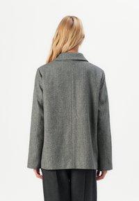 Cappotto grigio in misto lana con motivo a zigzag, maniche lunghe, ampia colletto e taglio dritto, mostrato dal retro.